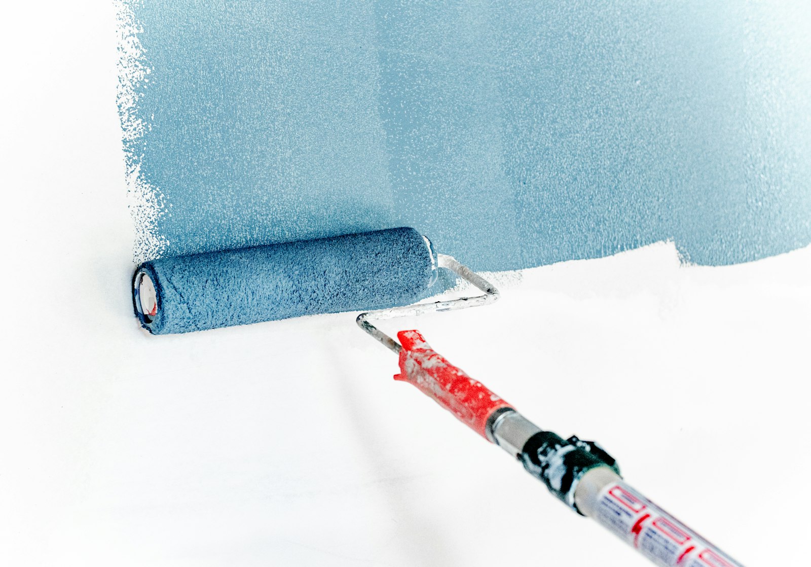 A roller applying paint to a wall